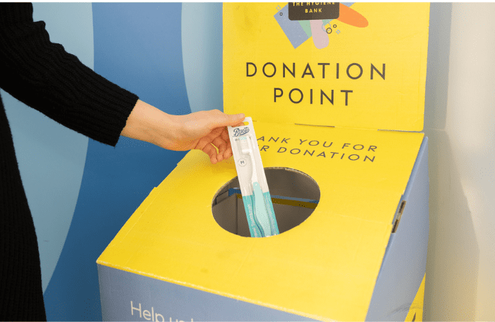 A hand putting a toothbrush in the hygiene bank donation box