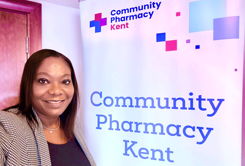 Shirley standing next to a board which says Community Pharmacy Kent