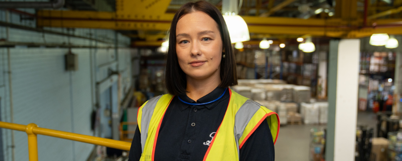 An engineering apprentice standing in the warehouse in Boots uniform